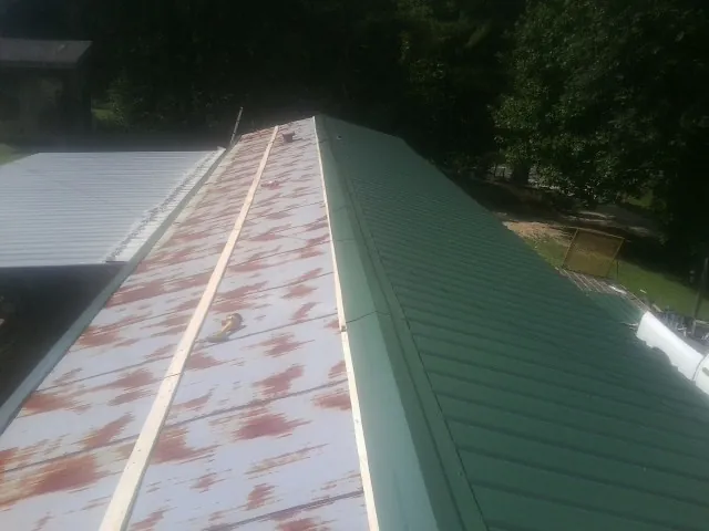 Old rusted panels beside newly installed green metal roofing — Wind Damage Roof Repair by Roofing Brothers in East Helena