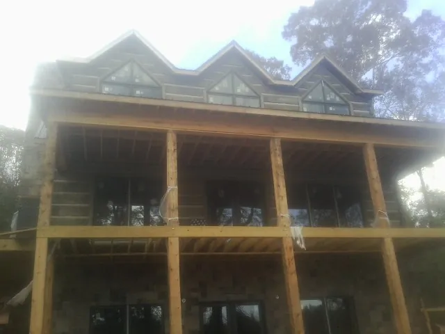 Dormers and porch framing on a large log home under construction — Roof Coating work by our crew in East Helena