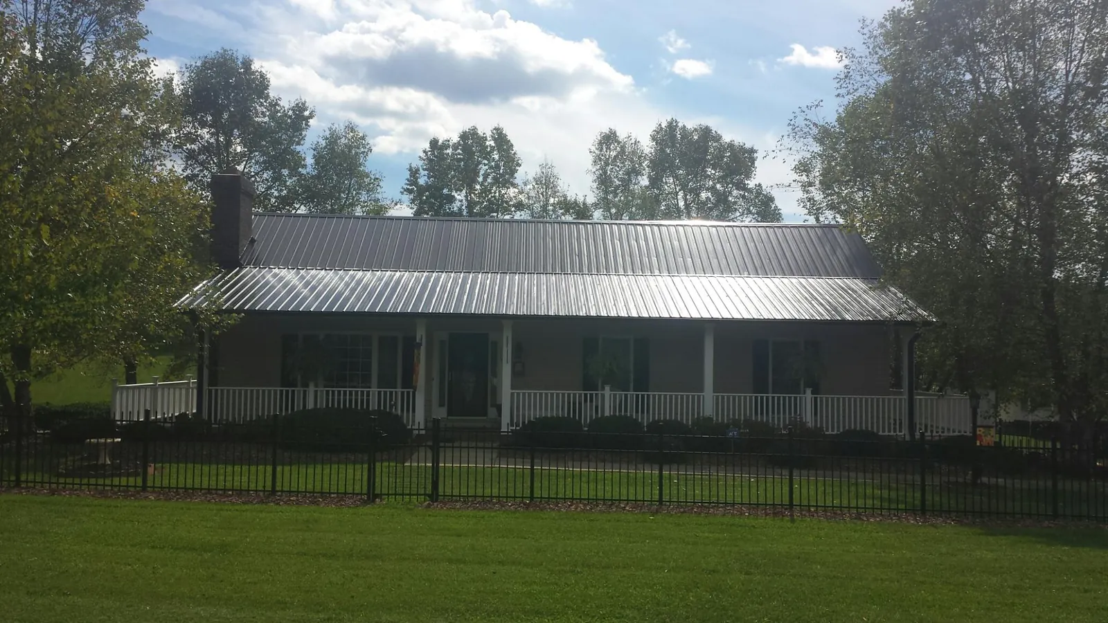 Gray metal roof on a brick ranch with a full width front porch — Gutter Guard Installation work by our crew in East Helena
