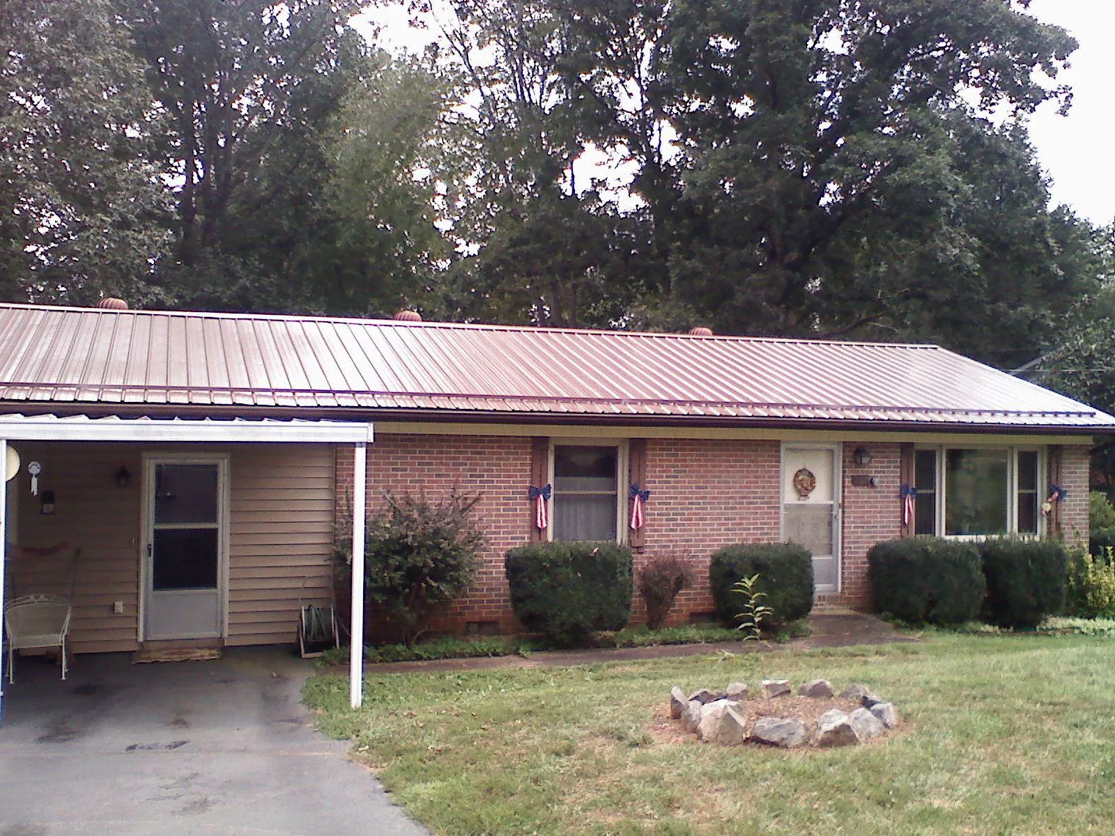 Bronze metal roof and carport on a brick ranch home — Roof Repair work by our crew in East Helena