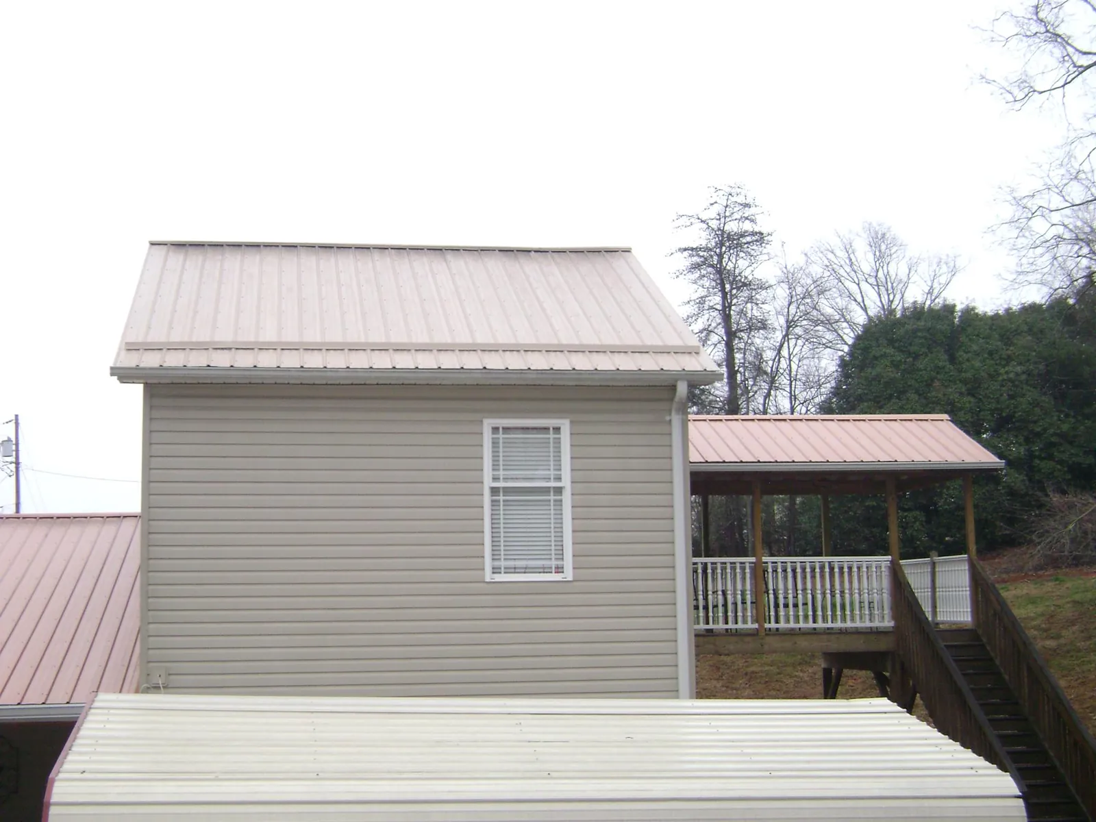 Tan metal roofs on a two story addition and attached porch, from a Roof Replacement job in East Helena