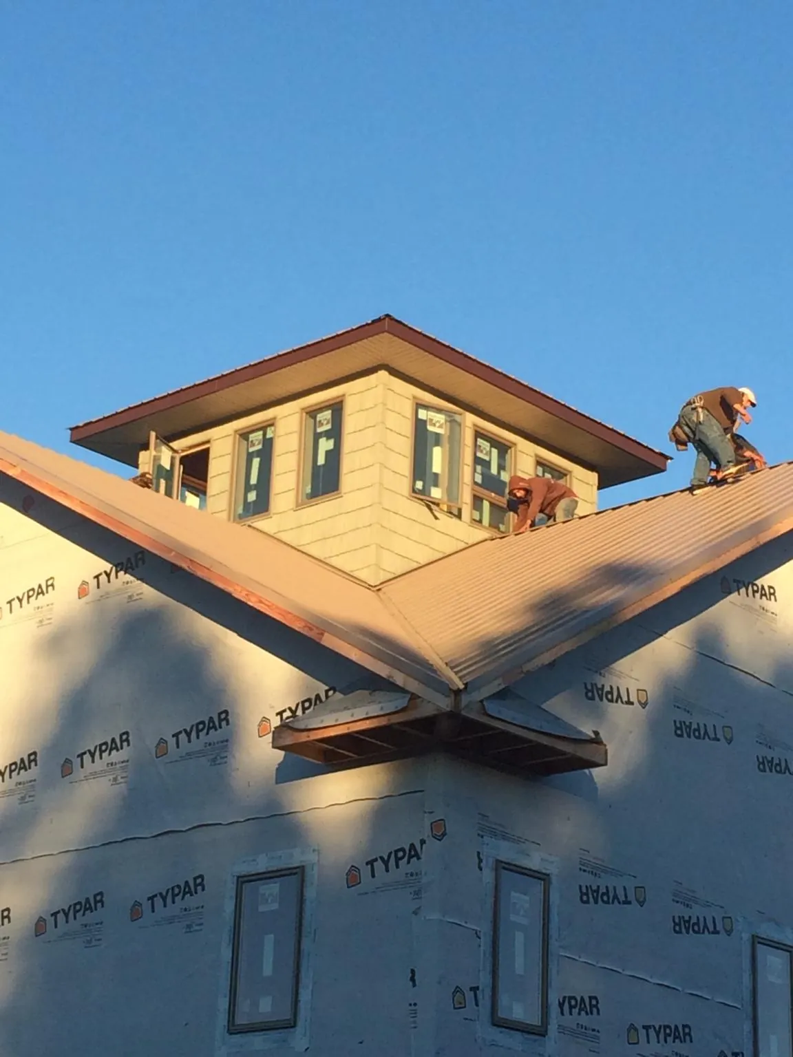 Roofers working around a rooftop cupola on a new metal roof at sunset — Roof Waterproofing in East Helena by Roofing Brothers